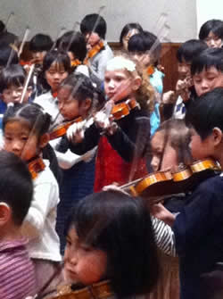 Sydney plays violin in a group of all Japanese kids
